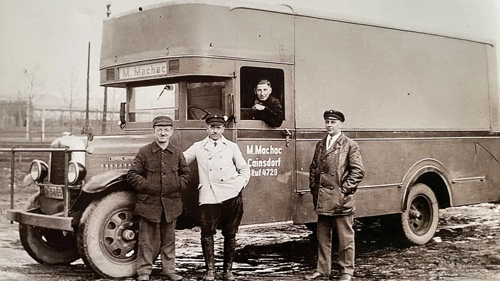Drei Männer und ein Fahrer neben einem Machac-Möbelwagen auf dem Hof in Cainsdorf.