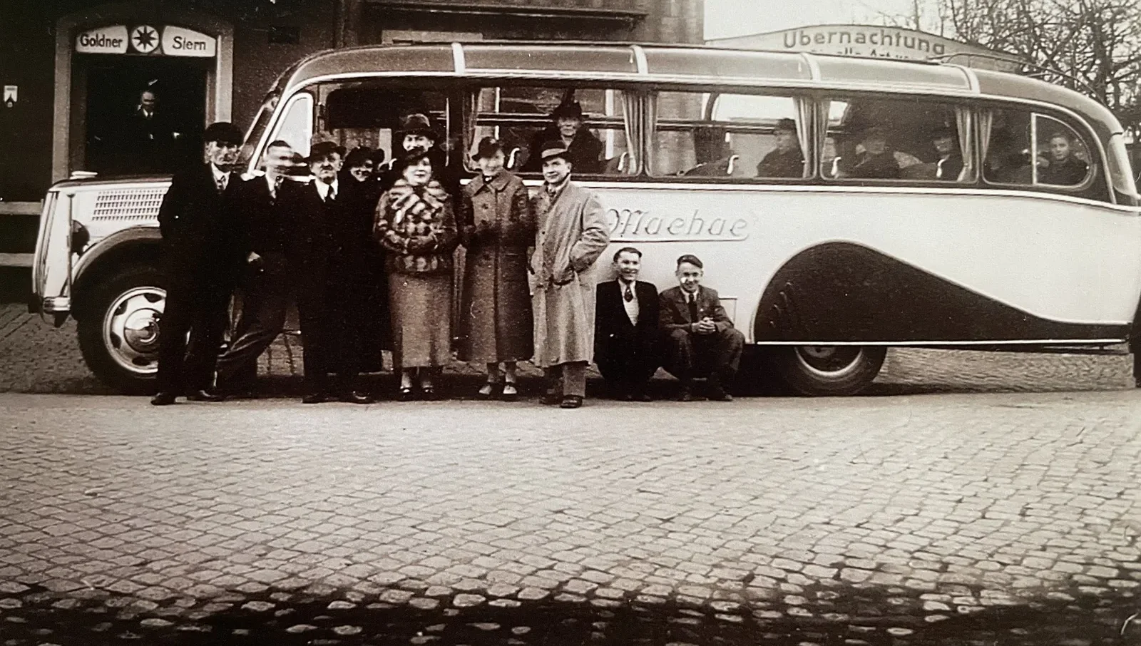 Ein Machac-Reisebus der 1930er-Jahre vor dem Gasthof Goldner Stern, Fahrgäste davor aufgereiht.
